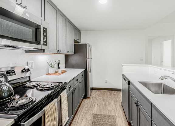 A kitchen with a black stove top oven and a black microwave above it.