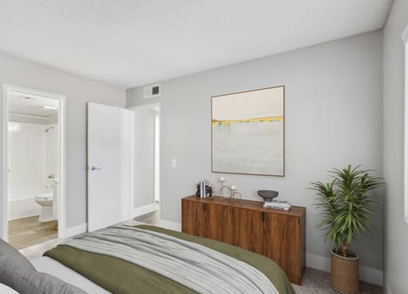 a bedroom with a bed and a potted plant    and a bathroom