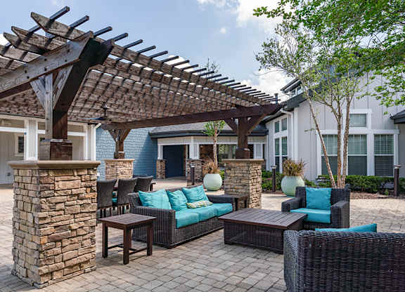 A patio with a stone pillar and a pergola.