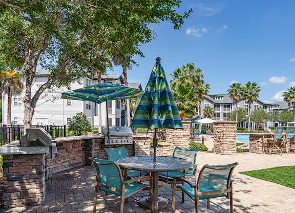 A patio with a table and chairs under a green and white striped umbrella.