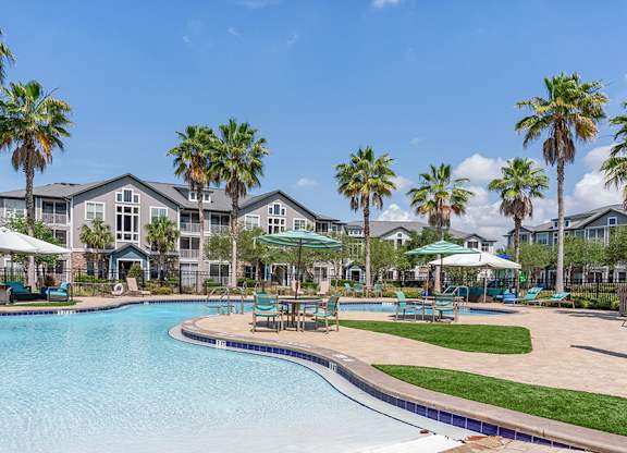 A swimming pool surrounded by palm trees and lounge chairs.