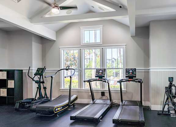 A gym with treadmills and a fan.