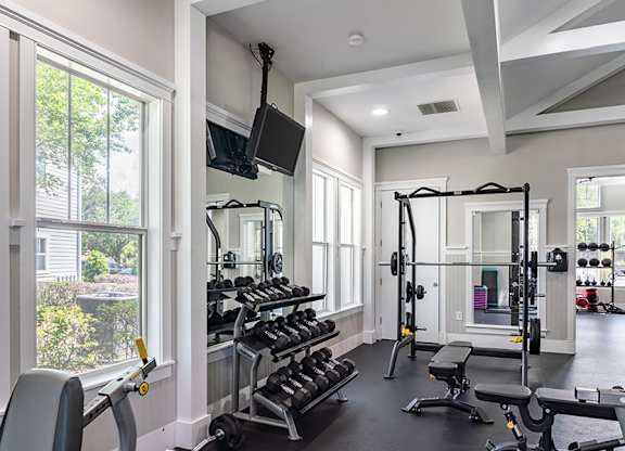 A well-lit home gym with a variety of exercise equipment.