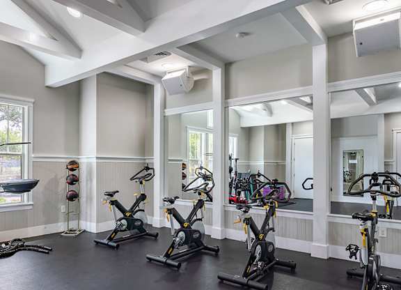 A gym with a row of stationary bikes and a mirror on the wall.