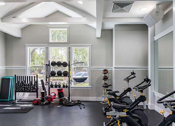 A gym with a row of stationary bikes and a variety of other equipment.