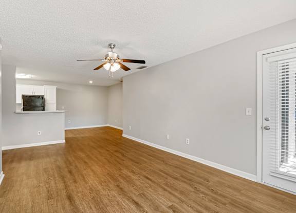 Model living room with wood flooring and ceiling fan at Huntington Place in Sarasota, Florida.