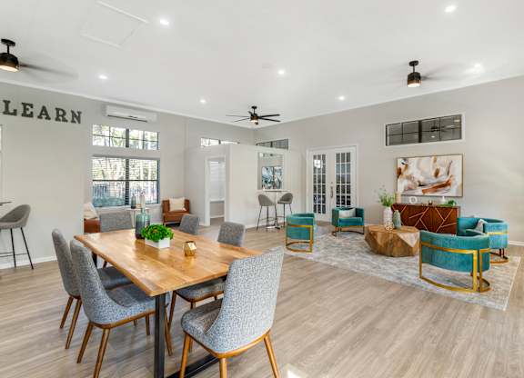A room with a dining table and chairs, a sofa, and a rug.