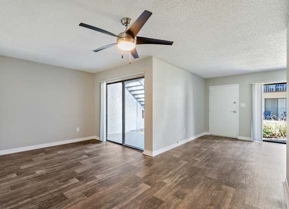 Model room with ceiling fan, sliding door, and wood flooring at Oasis at Bayside in Largo, FL.