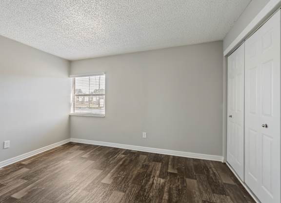 Model bedroom with window and wood flooring at Oasis at Bayside in Largo, FL.