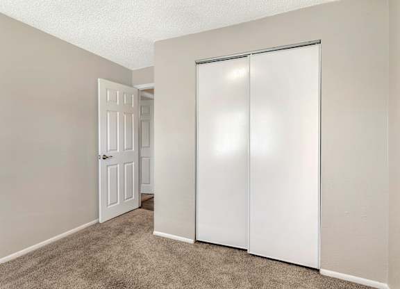 Model bedroom with sliding closet door and carpet flooring at Park at 7200 in Jacksonville, Florida.