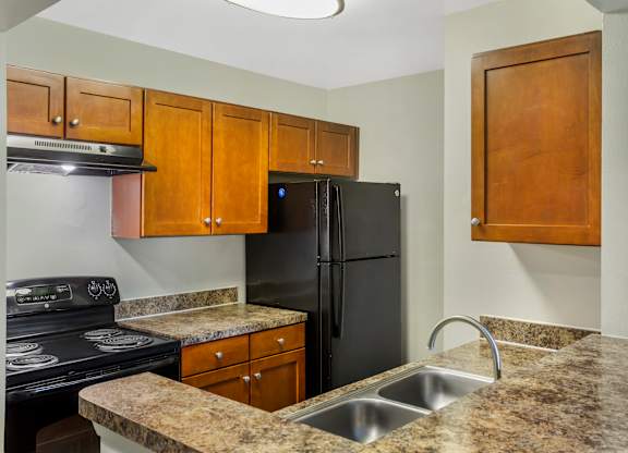 A kitchen with granite countertops and a black refrigerator.