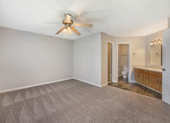 A room with a ceiling fan and carpeted floor.