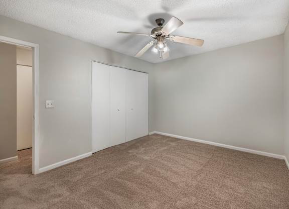 A room with a ceiling fan and carpeted floor.