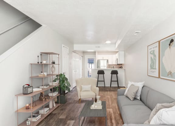 Model living room with a couch and a coffee table and stairs leading up to the 2nd floor.