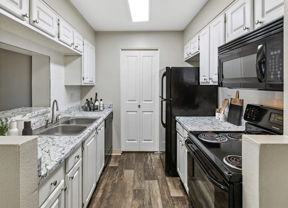 a kitchen with white cabinets and black appliances