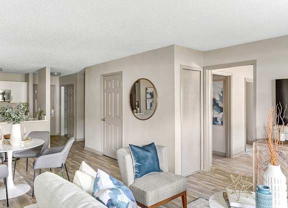 Model Living Room with Wood-Style Flooring and View of Kitchen at Mirage on Kernan Apartments located in Jacksonville, FL.