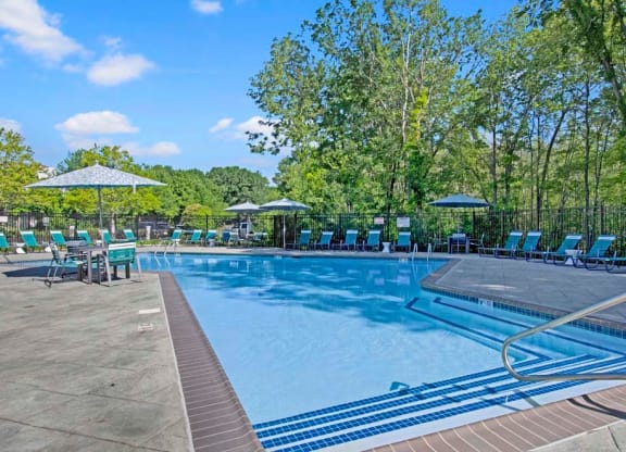 a swimming pool with chaise lounge chairs and umbrellas