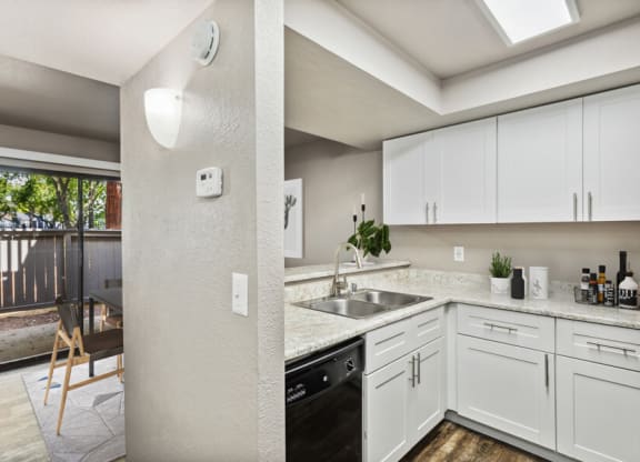 a kitchen with white cabinets and a black dishwasher