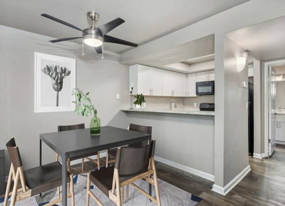 a dining area with a table and chairs and a ceiling fan