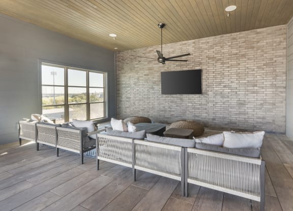 a living room with a couch and a tv on a brick wall