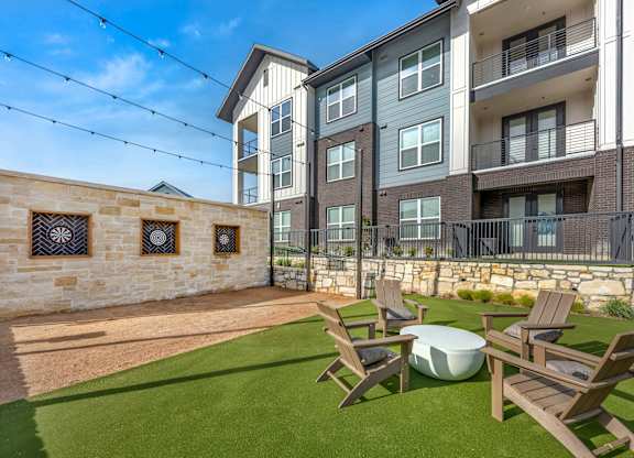 A sunny day at a modern apartment complex with a stone wall and a lawn.