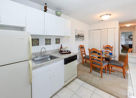 A kitchen with white cabinets and a white refrigerator.