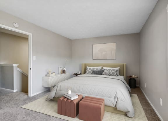 Model apartment bedroom with a large bed and a carpeted floor