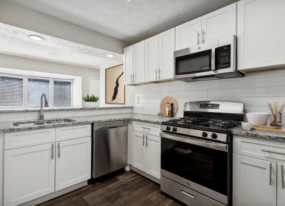 Model apartment kitchen with white cabinets and stainless steel appliances