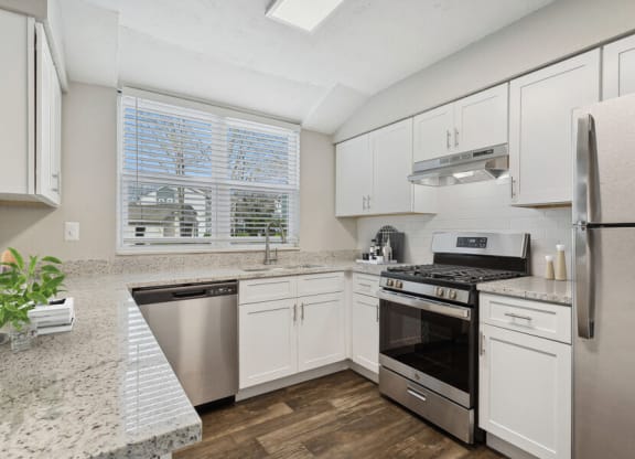Model apartment kitchen with white cabinets and stainless steel appliances