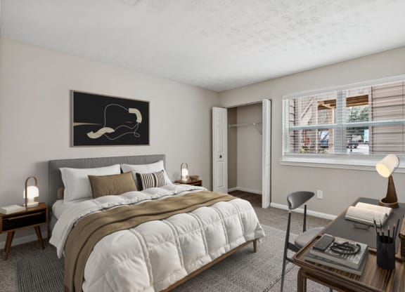 Model apartment bedroom with a bed and a desk and a window