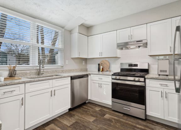 Sandy Springs, GA, Apartments Near Perimeter Mall - Edgewater at Sandy Springs - White Kitchen With Shaker Cabinets, Granite-Style Counters, Stainless Steel Appliances, And A Large Window Over Sink.