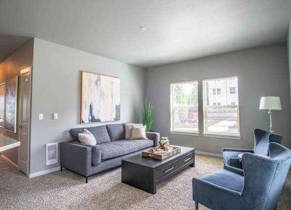 A living room with a grey couch, a blue chair, and a coffee table.