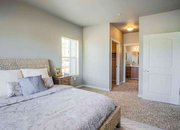 A bedroom with a bed, nightstand, and a window.
