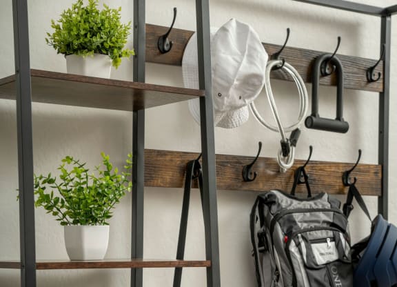 a metal shelving unit with hooks and a backpack on it and plants on the shelves