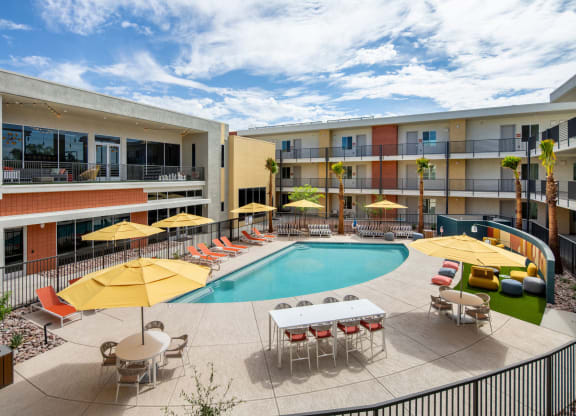 a swimming pool with yellow umbrellas and red and white chairs