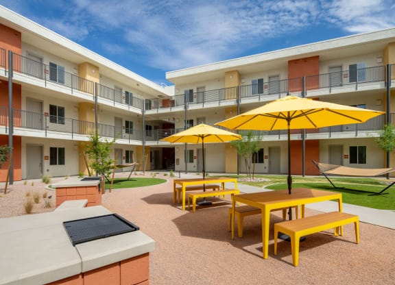 a courtyard with yellow tables and yellow umbrellas