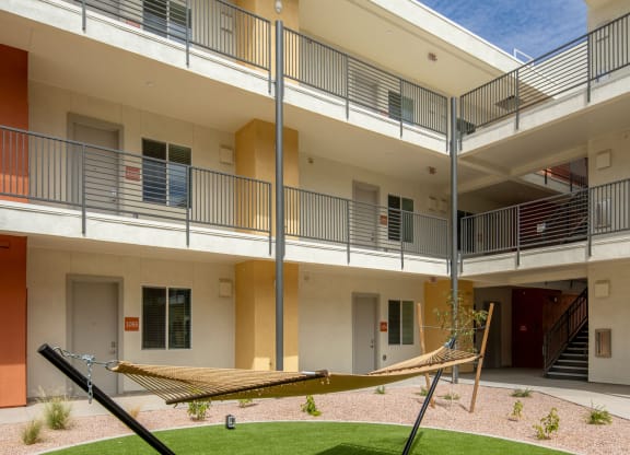 a hammock sits in the courtyard of an apartment building