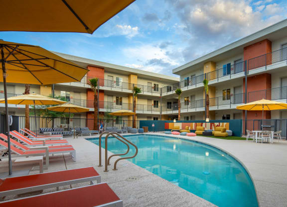 a swimming pool with yellow umbrellas and red and white lounge chairs