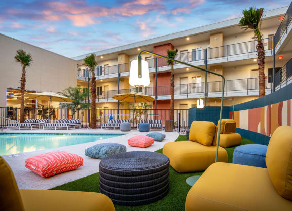 a courtyard with couches and pillows and a pool in front of a building