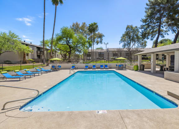 a swimming pool with blue lounge chairs