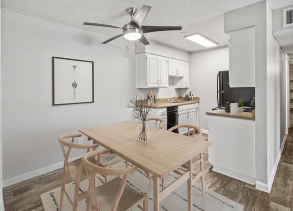 A dining area with a table and chairs and a kitchen in the background