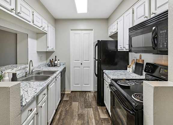 a kitchen with white cabinets and black appliances