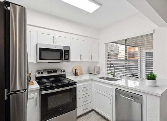 Model Kitchen with White Cabinets and Wood-Style Flooring at Horizon Apartments located in Santa Ana, CA.