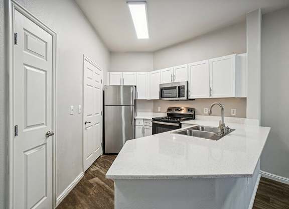 Model Kitchen with Wood-Style Flooring, White Cabinets, and Stainless-Steel Appliances at Altitude on Fifth Apartments located in Salt Lake City, UT.