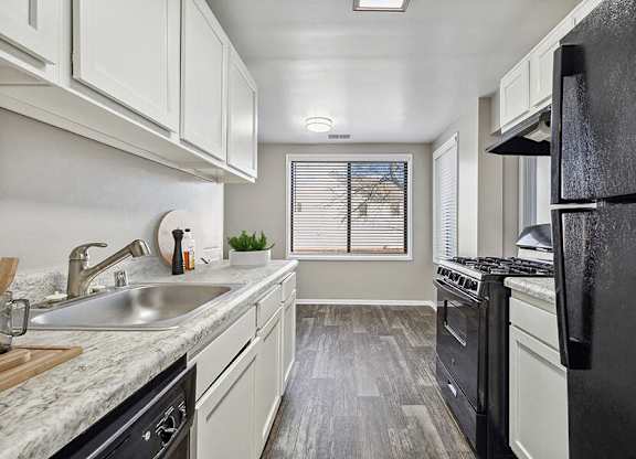 Silver Spring, MD Apartments for Rent - Spring Parc - Updated Galley Kitchen With White Cabinets, Marble Look Counters, Gas Range, Black Refrigerator, And Wood Style Flooring