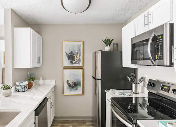Model Kitchen with White Cabinets and Wood-Style Flooring at Mirage on Kernan Apartments located in Jacksonville, FL.