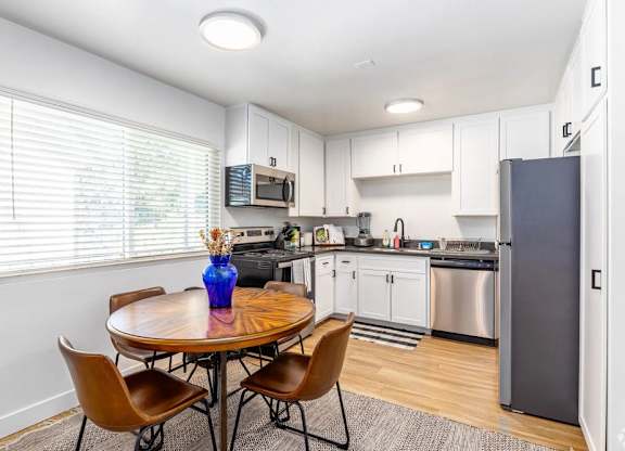 A kitchen with a table and chairs and a refrigerator.