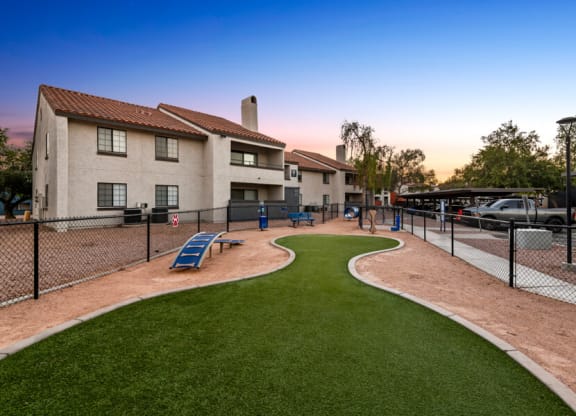 a fenced in dog park at sunset with apartments in the background at Lore South Mountain, Phoenix, 85044