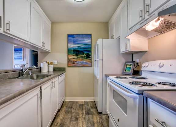 A kitchen with white cabinets and a painting on the wall.