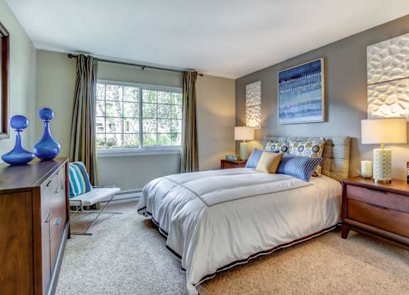 A bedroom with a large bed and a window with curtains.